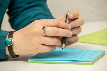 a person writing on a notepad with a pen