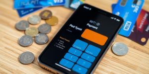 Smartphone with payment app, coins, and credit cards.