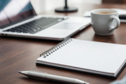 Business workspace with laptop, notepad, and coffee.