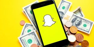 Smartphone with Snapchat logo and money on table.