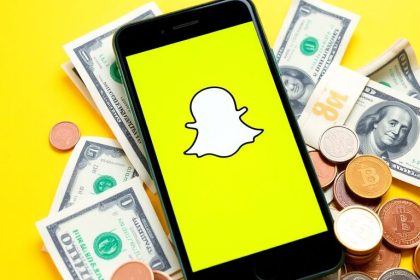 Smartphone with Snapchat logo and money on table.