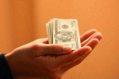 Hand holding cash for individual hardship grants.