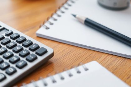 Calculator and notepad on a wooden desk.