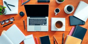 Flat lay of business tools on a wooden desk.