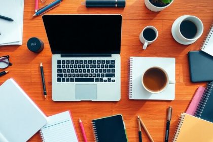 Flat lay of business tools on a wooden desk.